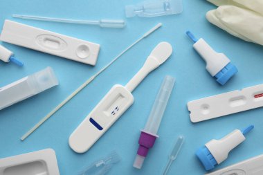 Açık mavi arkaplan üzerinde tek kullanımlık ekspres test kitleri, düz yatıyordu