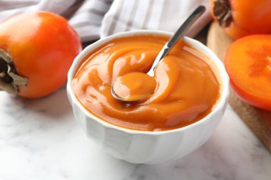 Lezzetli hurma reçeli ve beyaz mermer masada taze meyveler, yakın plan.