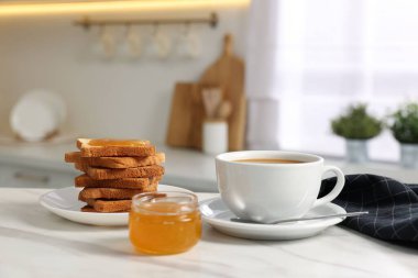 Kahvaltı mutfakta servis edilir. Taze tost, kahve ve bal beyaz mermer masada.