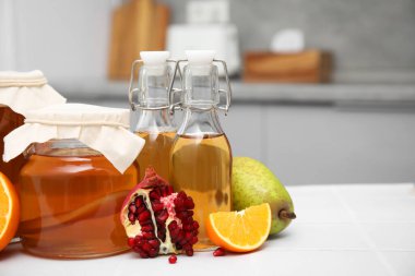 Ev yapımı mayalanmış kombu çayı ve mutfaktaki beyaz masada taze meyveler. Metin için boşluk