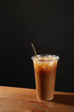 Sütlü buzlu kahve, ahşap masada siyah arka planda, metin için yer var.