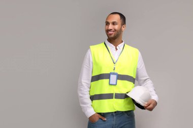 Gri arkaplan üzerinde sabit şapka ve rozetli mühendis, metin için boşluk