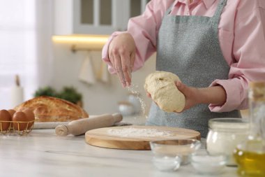 Ekmek yapıyorum. Mutfaktaki beyaz masada hamur tutan kadın, yakın plan.