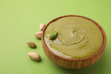 Fıstıklı krema kasede ve fındıklı yeşil arka plan, yakın plan. Metin için boşluk