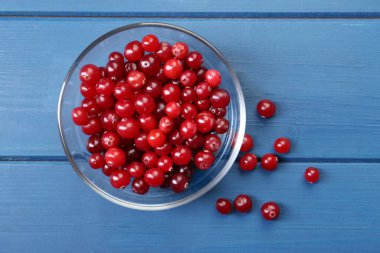 Taze taze kızılcıklar cam kasede mavi ahşap masada, üst tarafta.