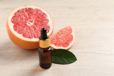 Bir şişe greyfurt yağı ve hafif ahşap masada taze meyve. Metin için boşluk