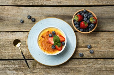 Böğürtlenli ve nane şekerli nefis creme brulee ahşap masada servis edilir.