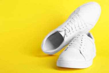 Sarı arka planda bir çift şık beyaz spor ayakkabı. Metin için boşluk