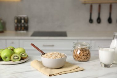 Kahvaltı vakti geldi. Lezzetli yulaf ezmesi, meyve, granola ve süt beyaz mermer masada.