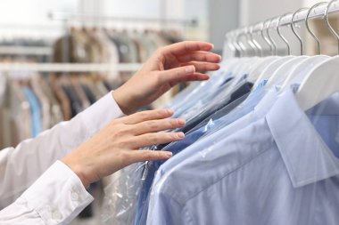 Kuru temizleme servisi. Kadın gömleğini plastik torbaya koyuyor, kapalı mekandan, yakın plan.