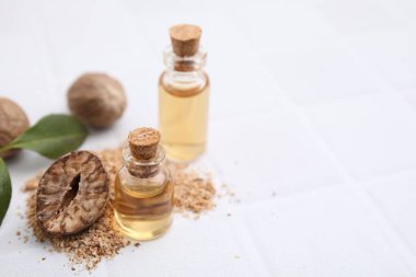Nutmeg esaslı yağ ve fındıklar beyaz masada. Metin için boşluk