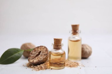 Nutmeg esaslı yağ ve fındıklar beyaz masada. Metin için boşluk