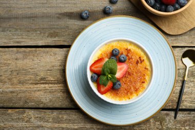 Böğürtlenli ve nane şekerli nefis creme brulee, ahşap masada servis edilir, düz yatar. Metin için boşluk