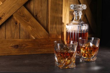 Buzlu viski bardakta ve gri masada şişe, mesaj için yer var.