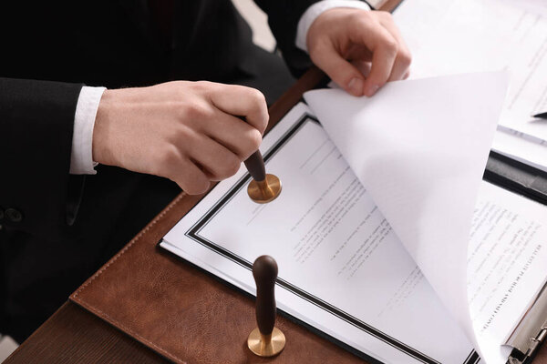 Нотариальный штамповочный документ за деревянным столом в офисе, крупный план