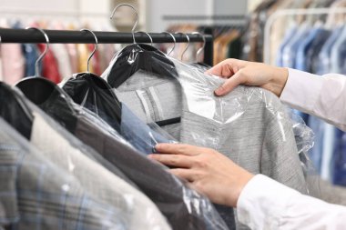 Kuru temizleme servisi. Kadın plastik torba içinde ceketini alıyor, kapalı mekandan, yakın plan.