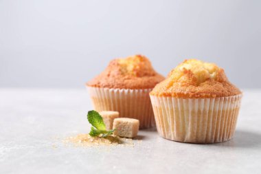 Açık gri desenli masada nefis tatlı kekler ve esmer şeker, yakın plan. Metin için boşluk