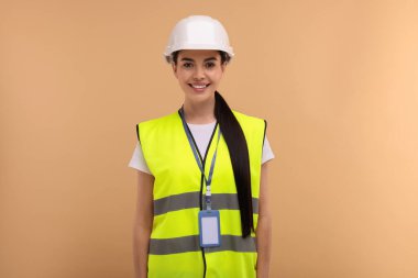 Bej arka planda kasketi ve rozeti olan mühendis.