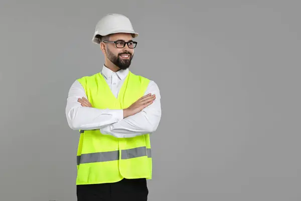 Engineer in hard hat on grey background, space for text