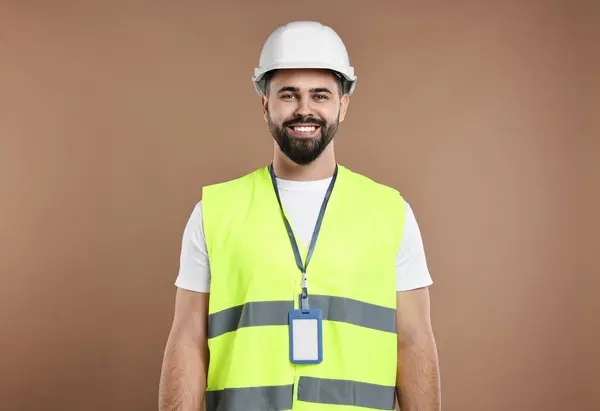 Engineer with hard hat and badge on brown background