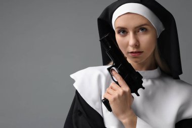 Gri arka planda silah tutan rahibe kıyafetli bir kadın. Metin için boşluk