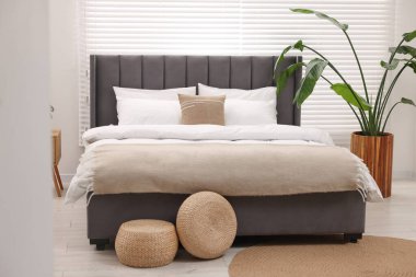 Şık bir yatak odasında büyük bir yatak ve bitkiler. İç tasarım