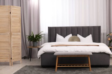 Şık bir yatak odası. Büyük yatak odası, kanepe, lamba ve çiçek.