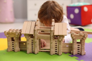 Küçük çocuk odasındaki yapboz paspası üzerinde tahta giriş kapısıyla oynuyor. Seçici bir odak noktası. Çocuk oyuncağı