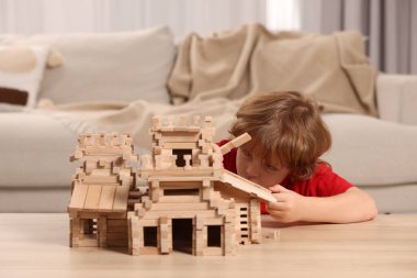 Odadaki tahta kaleyle oynayan şirin küçük çocuk. Çocuk oyuncağı