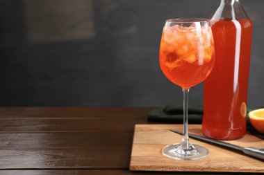 Aperol sprey kokteyli ve buz küpleri cam ve şişe ahşap masa üzerinde, mesaj için yer var.