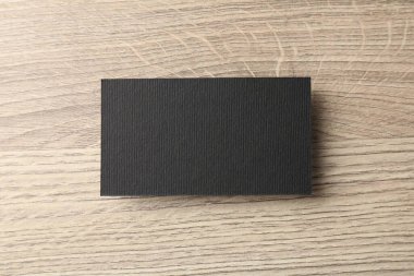 Ahşap masanın üstünde boş siyah kartvizit, üst manzara. Tasarım için model