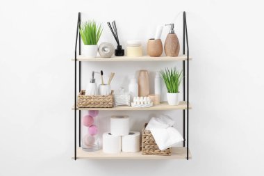 Farklı banyo aksesuarları, kişisel bakım ürünleri ve kapalı alandaki yapay bitkiler.