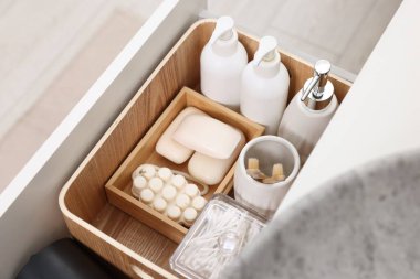 Farklı banyo aksesuarları ve kişisel bakım ürünleri kapalı çekmecede, üst tarafta.