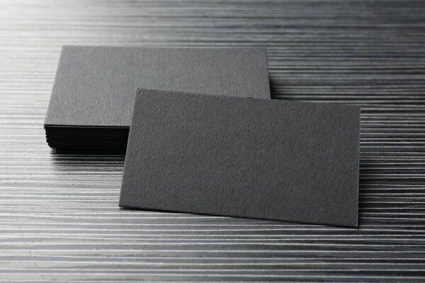 Blank black business cards on wooden table, closeup. Mockup for design