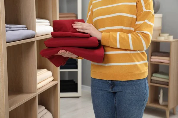Woman with stack of bed linens in shop, closeup