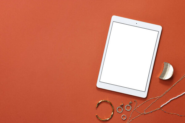 Modern tablet and bijouterie on color background, flat lay. Space for text