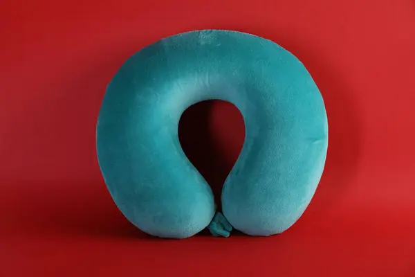 One turquoise travel pillow on red background