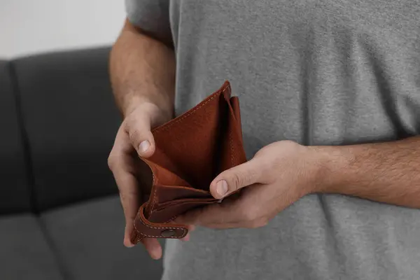 Man with empty wallet at home, closeup