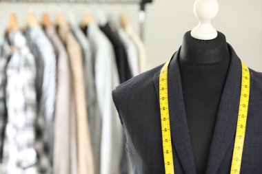 Tamamlanmamış ceketli manken ve terzi dükkanında mezura, yakın plan. Metin için boşluk