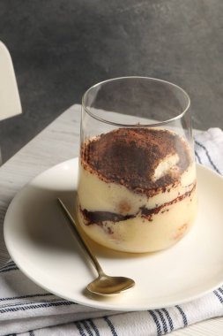 Lezzetli tiramisu beyaz ahşap masada cam içinde.