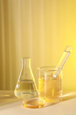 Laboratuvar analizi. Sarı arka planda farklı cam eşyalar var.