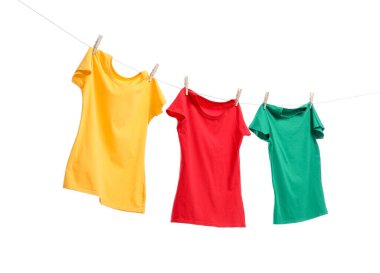 Beyaz arka planda çamaşır ipinde kuruyan farklı parlak tişörtler.
