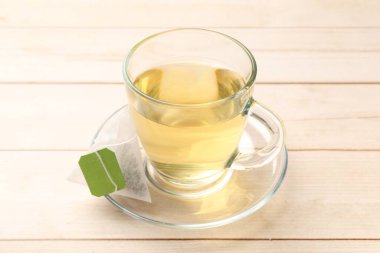 Çay poşeti ve cam bardak açık ahşap masada, yakın plan.