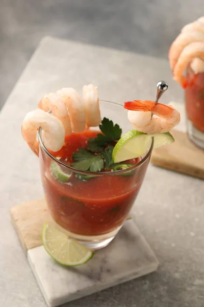 Tasty shrimp cocktail with sauce in glasses and lime on light grey table, closeup