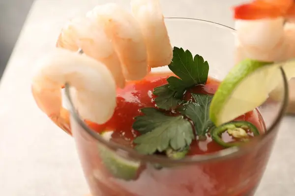 Tasty shrimp cocktail with sauce, parsley and lime in glass on table, closeup