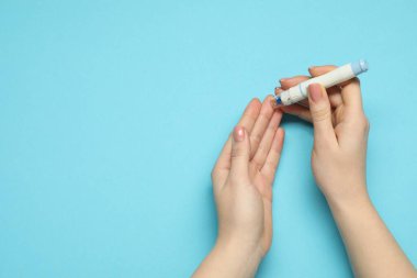 Diyabet. Glikoz testi. Mavi arka planda tükenmez kalem kullanan bir kadın. Metin için boşluk