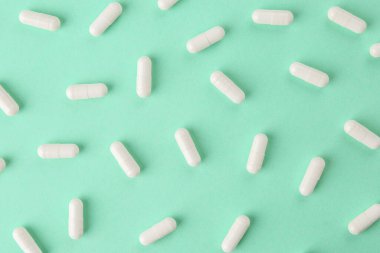 Turkuaz zemin üzerinde vitamin kapsülleri, düz yatış