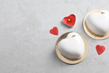 Sevgililer Günü. Lezzetli kalp şeklinde kekler, mum ve konfeti açık gri masada, düz konfeti. Metin için boşluk