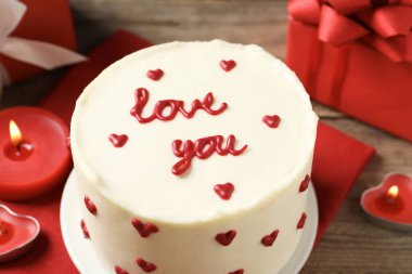 Mesajlı Bento pastası Love You ve ahşap masada mumlar, yakın plan. Sevgililer Günü sürprizi