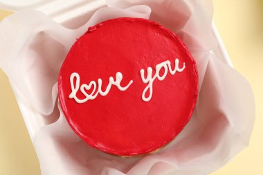 Bento keki ve Love You paket servis kutusuyla bej masanın üstünde, en üstte. Sevgililer Günü sürprizi